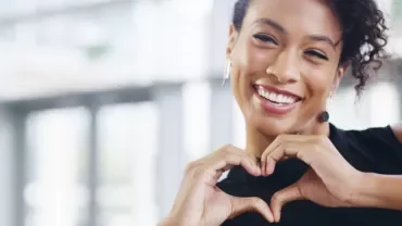 Personne souriante formant un cœur avec ses mains.