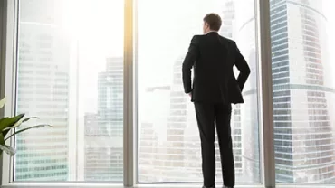 Personne debout devant une grande fenêtre avec vue sur des gratte-ciel.